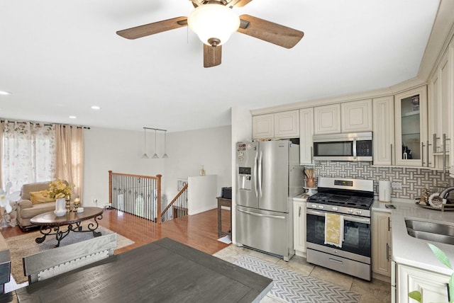 kitchen with sink, decorative backsplash, cream cabinetry, decorative light fixtures, and stainless steel appliances