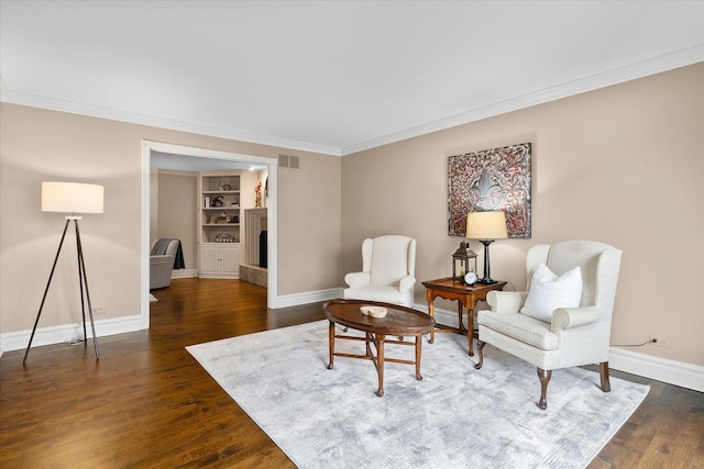 sitting room featuring dark wood-style floors, visible vents, baseboards, and crown molding