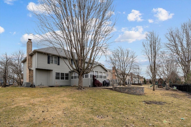 back of property with a chimney, a playground, a yard, and central AC