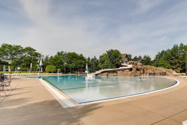 community pool with a water slide and a patio area