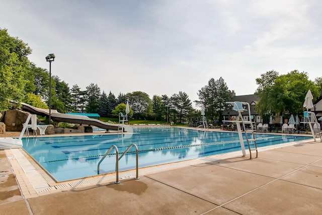 community pool with a water slide and a patio