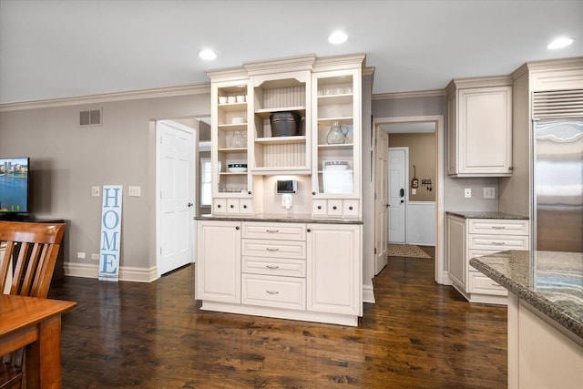 kitchen with built in refrigerator, visible vents, dark wood-type flooring, and crown molding