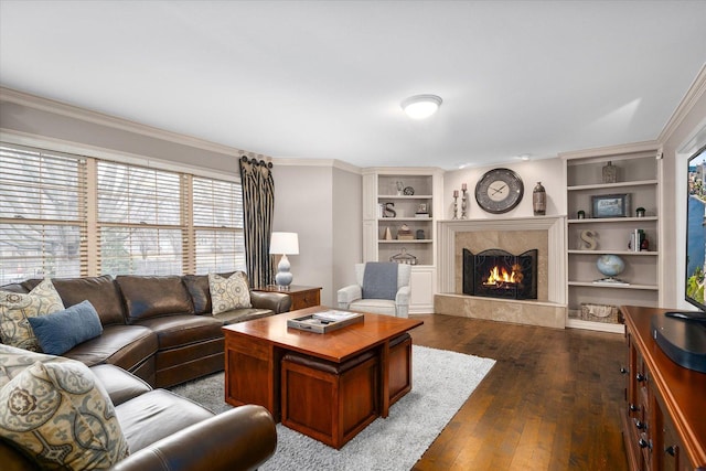 living room with a fireplace, built in features, dark wood finished floors, and crown molding