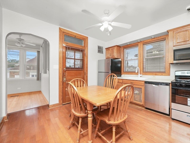 dining space featuring ceiling fan, sink, and light wood-type flooring