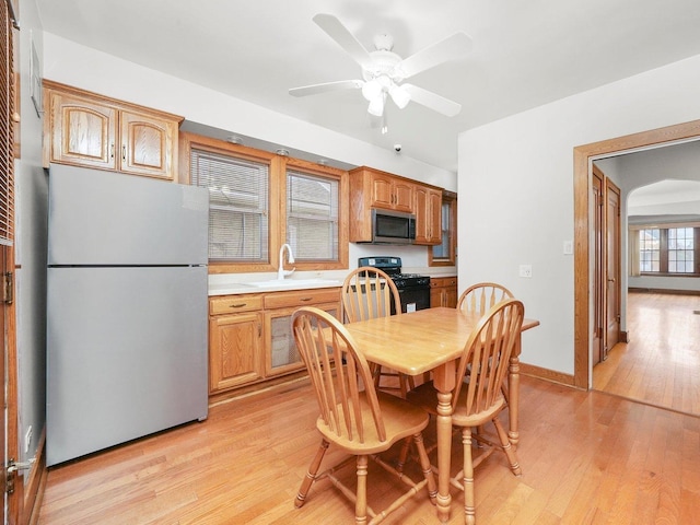 dining area with a healthy amount of sunlight, sink, and light hardwood / wood-style flooring