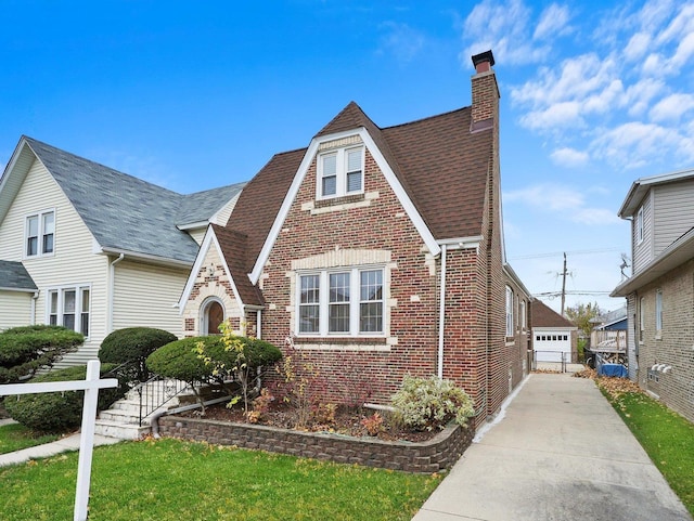 tudor house featuring an outbuilding, a front yard, and a garage