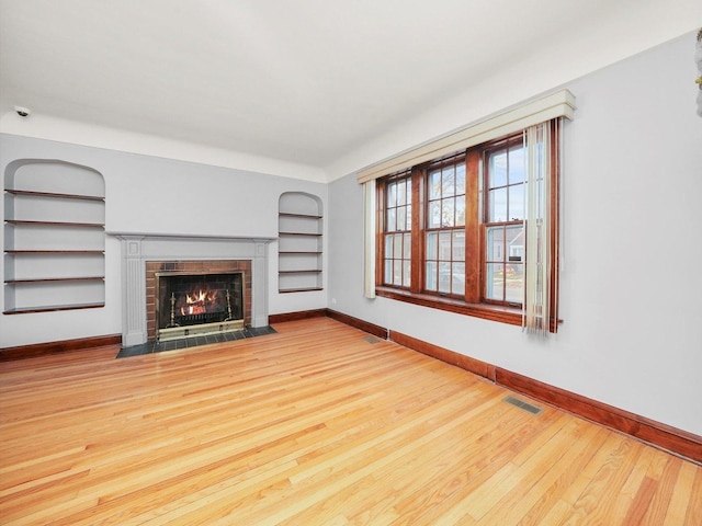 unfurnished living room featuring light hardwood / wood-style flooring and built in features