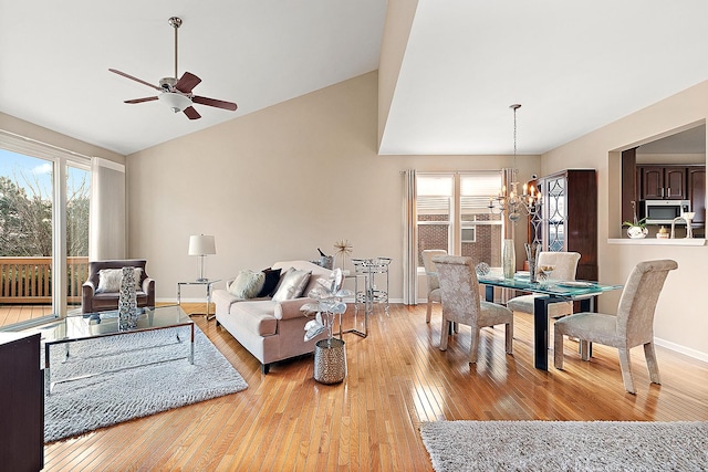 living room with ceiling fan with notable chandelier, light hardwood / wood-style flooring, and lofted ceiling