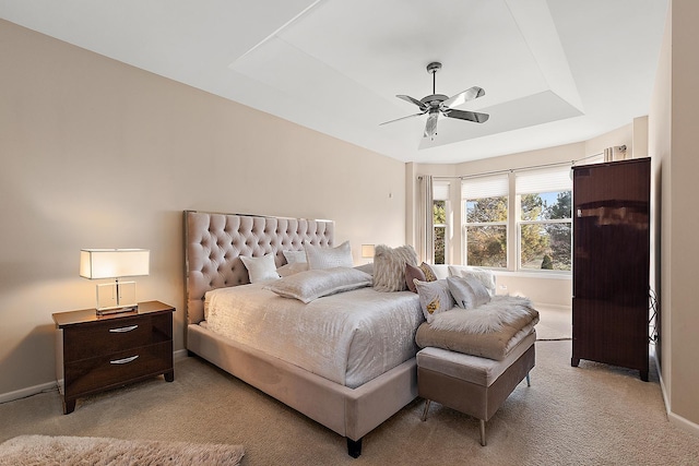 carpeted bedroom with ceiling fan and a tray ceiling