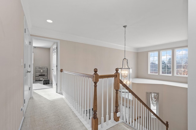 hall with light carpet, crown molding, and a chandelier