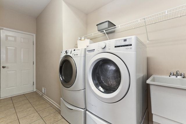 laundry room featuring washer and dryer, light tile patterned floors, and sink