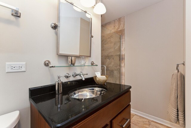 bathroom featuring tiled shower, toilet, and sink