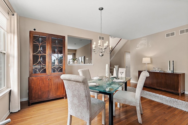 dining space with an inviting chandelier and light hardwood / wood-style flooring