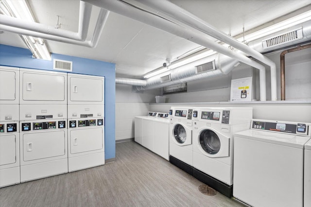 clothes washing area featuring light wood-type flooring, stacked washing maching and dryer, and washer and clothes dryer