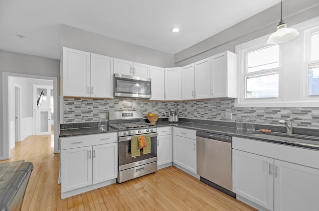 kitchen with sink, white cabinetry, stainless steel appliances, and light hardwood / wood-style flooring