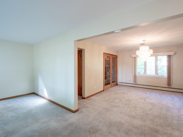 spare room featuring carpet flooring, an inviting chandelier, and a baseboard heating unit