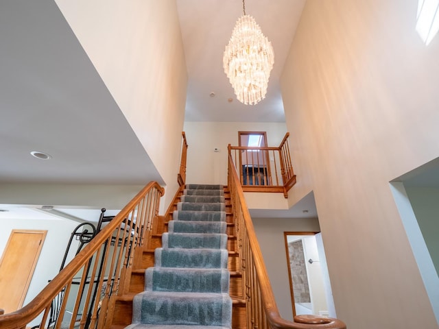 staircase featuring a towering ceiling and a chandelier