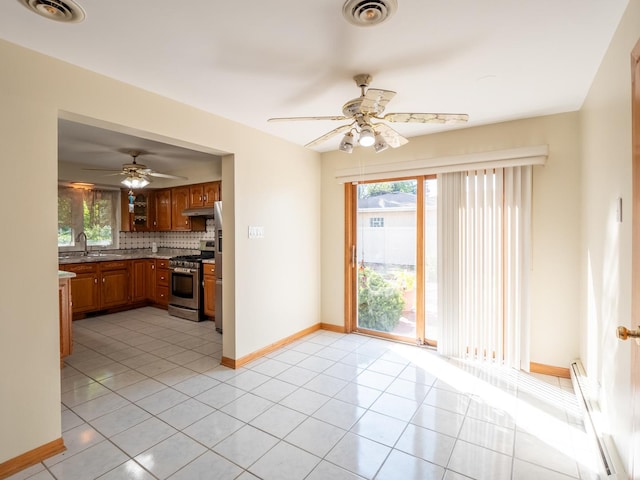 kitchen with tasteful backsplash, sink, light tile patterned floors, and stainless steel appliances