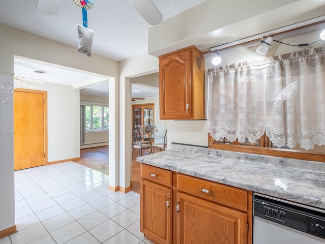 kitchen with light stone countertops, ceiling fan, baseboard heating, dishwasher, and light tile patterned flooring