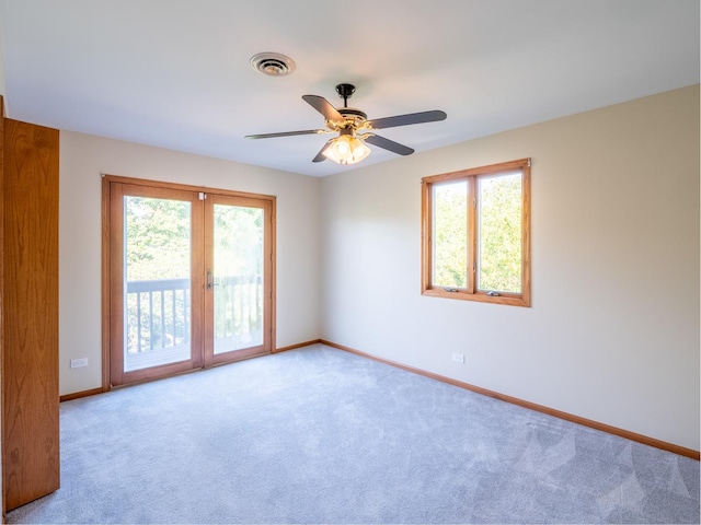 spare room with a wealth of natural light, french doors, ceiling fan, and light colored carpet