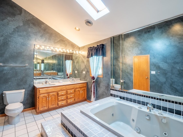 bathroom featuring tile patterned floors, vaulted ceiling with skylight, vanity, tiled tub, and toilet