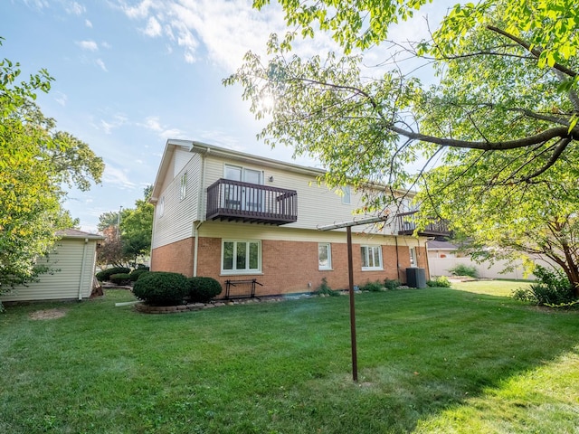 back of property featuring central AC unit, a balcony, and a yard