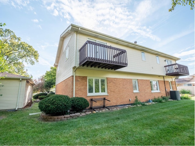 rear view of house featuring cooling unit, a balcony, and a yard