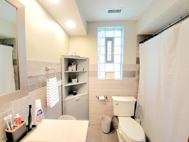 bathroom with toilet and tile walls