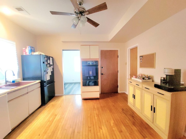 kitchen featuring black fridge, sink, ceiling fan, and light wood-type flooring