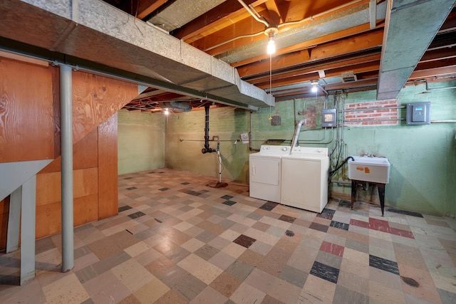 basement with washer and clothes dryer, sink, and electric panel