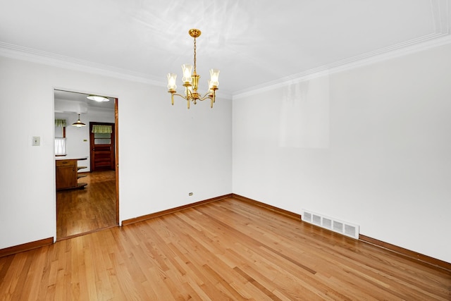 empty room with crown molding, an inviting chandelier, and hardwood / wood-style flooring