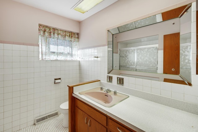 bathroom featuring toilet, vanity, tile patterned floors, and tile walls