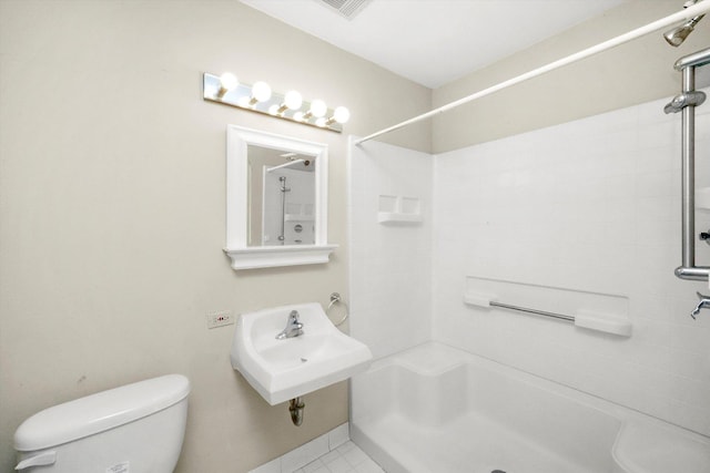 bathroom with tile patterned flooring, a tile shower, toilet, and sink