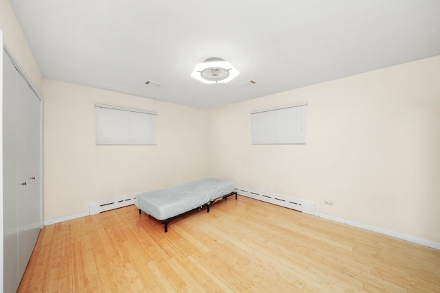 unfurnished room with wood-type flooring and a baseboard radiator