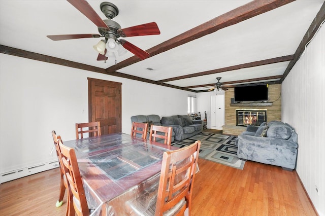 dining area with beam ceiling, ceiling fan, baseboard heating, hardwood / wood-style floors, and a fireplace