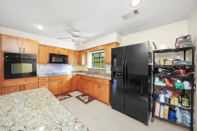 kitchen with ceiling fan, sink, light stone counters, light tile patterned floors, and black appliances