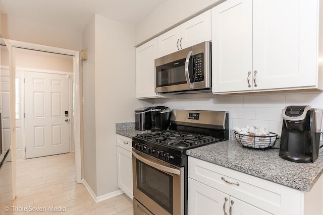 kitchen featuring appliances with stainless steel finishes, tasteful backsplash, white cabinetry, and light stone counters