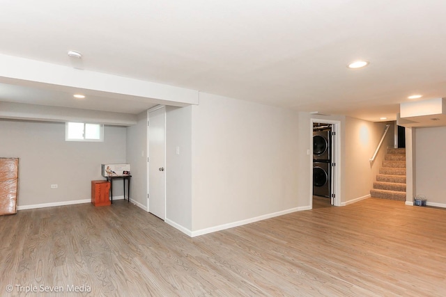 basement with stacked washing maching and dryer and light hardwood / wood-style flooring