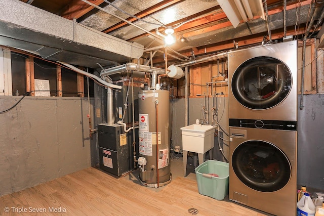 basement with hardwood / wood-style floors, sink, water heater, stacked washer / drying machine, and heating unit