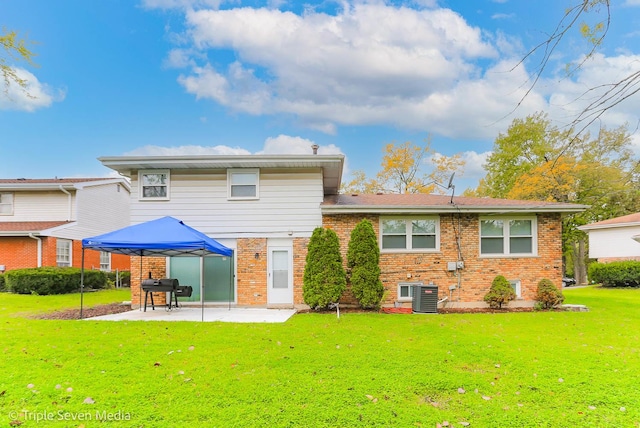 rear view of property featuring a lawn, a patio area, and central air condition unit