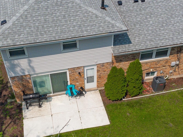 back of property with a yard, a patio, and central AC