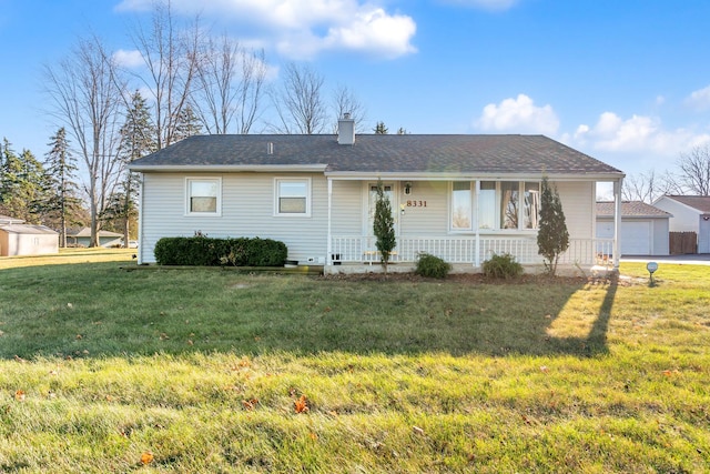 ranch-style house with covered porch, a garage, an outbuilding, and a front lawn