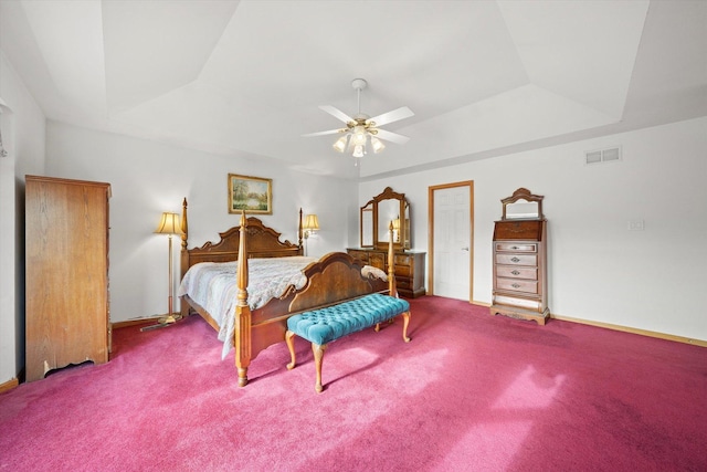 carpeted bedroom with a raised ceiling and ceiling fan