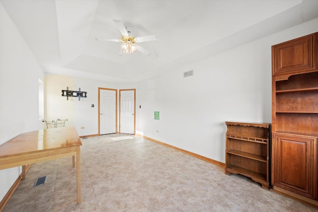 interior space with ceiling fan and a tray ceiling