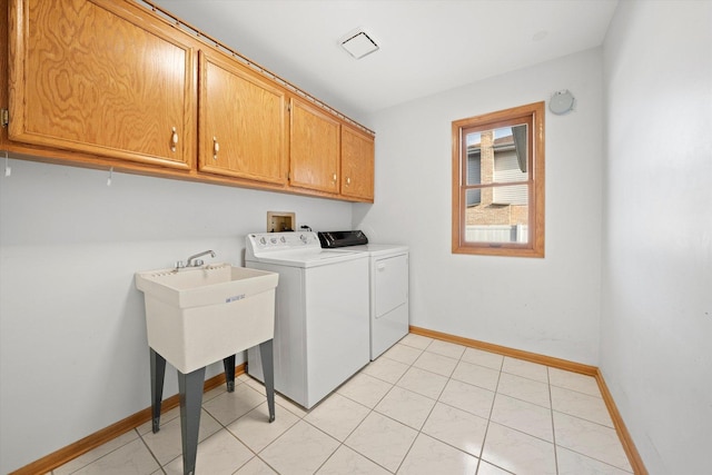 laundry room featuring washer and clothes dryer, light tile patterned flooring, and cabinets