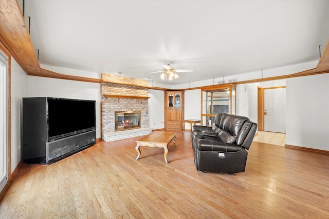 living room featuring ceiling fan, light hardwood / wood-style floors, and a brick fireplace