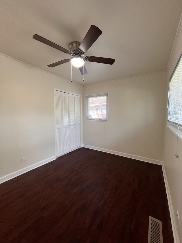 unfurnished bedroom featuring ceiling fan, dark hardwood / wood-style floors, and a closet