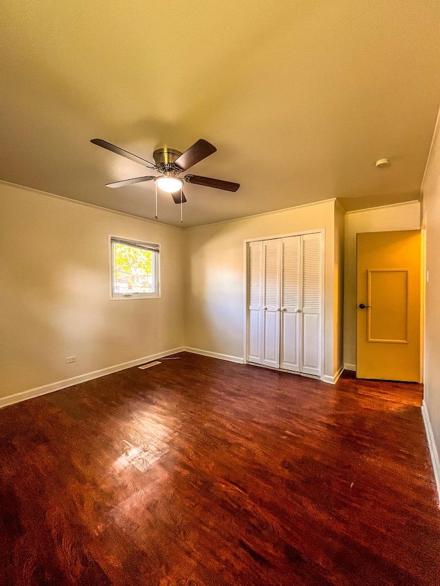 unfurnished bedroom with ceiling fan, dark hardwood / wood-style floors, and a closet