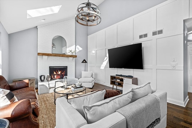 living room featuring a notable chandelier, high vaulted ceiling, a brick fireplace, and dark hardwood / wood-style floors