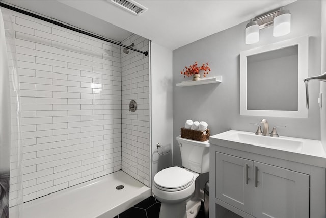 bathroom featuring vanity, toilet, and a tile shower